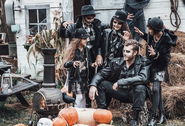 Photo scary family mother father daughters celebrating halloween terrifying black skull halfface makeup and witch costumes stylish imageshorrorfun at children's party in barn on streethatsjackets