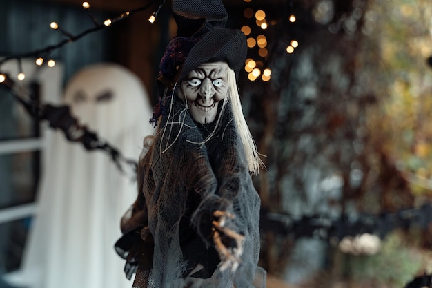 Scary flying hanging toy old witch on broomstickSparkling lightsDecorating of porch outdoor on street for halloween holidayDIY homestreet decorationentertainment for children horror atmosphere