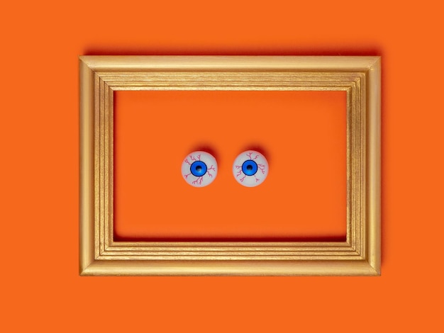 Scary and funny eyes in a frame on an orange background festive decoration for halloween