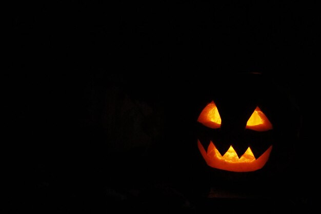 恐ろしい幽霊の顔が暗でハロウィーンに輝いています