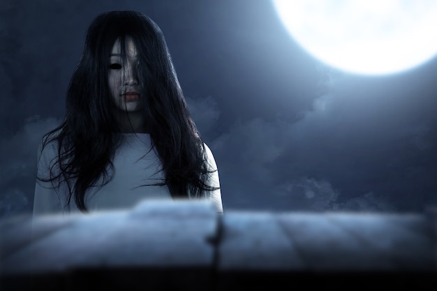 夜のシーンの背景で立っている怖い幽霊の女性。ハロウィーンのコンセプト