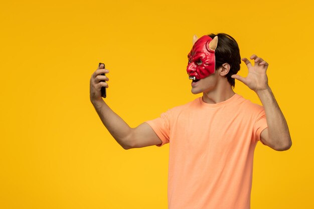 Scary mask young terrifying guy making scary hand gesture with the phone