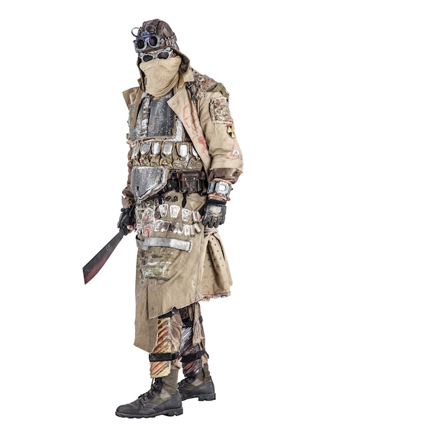 Photo scary post apocalyptic survivor in handmade armored clothes, armed with machete, dangerous creature with face hidden behind mask and glasses, in rags, standing with cold weapon in hand studio shoot