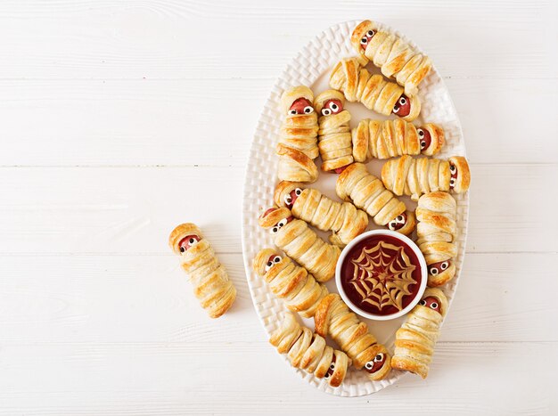 Mummie spaventose della salsiccia in pasta con gli occhi divertenti sulla tavola. decorazione divertente. cibo di halloween. vista dall'alto. disteso