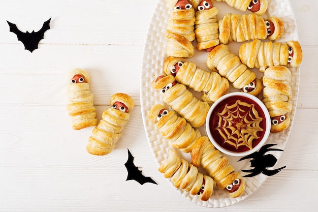 Mummie spaventose della salsiccia in pasta con gli occhi divertenti sulla tavola. decorazione divertente. cibo di halloween. vista dall'alto. disteso