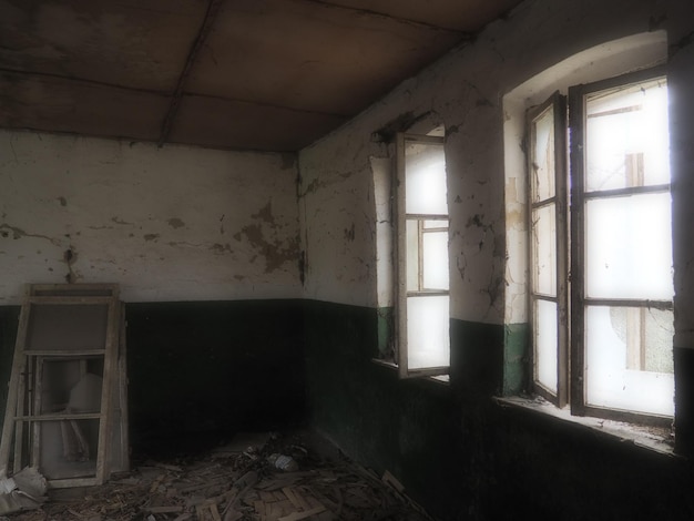 Scary windows Inside an abandoned house View of broken windows without a curtain Grunge scene Light shines through old wooden frames with broken glass The concept of abandonment and uselessness