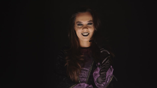 Scary woman dressed up like a witch for halloween over a black background