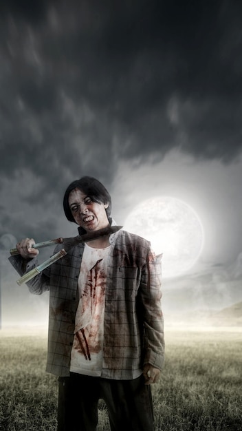 A scary zombie with blood and wounds on his body is walking while carrying a grass cutter on a meadow field Scary zombie Halloween concept