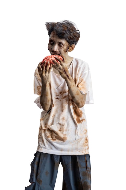 Foto uno zombie spaventoso con sangue e ferite sul corpo che cammina mentre mangia un cervello umano isolato su uno sfondo bianco