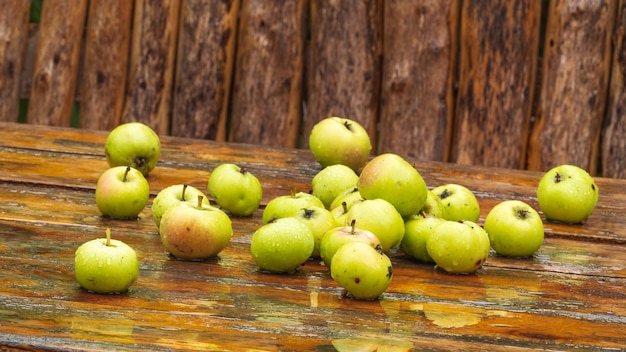 Scattered apples on wet wooden table