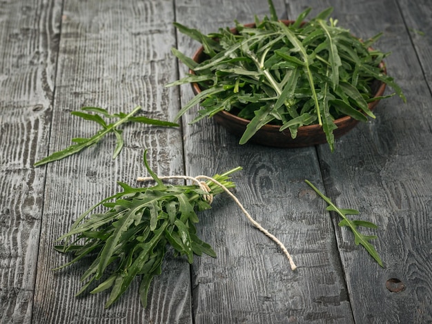 Scattered arugula leaves and a separate bundle lying on a wooden table