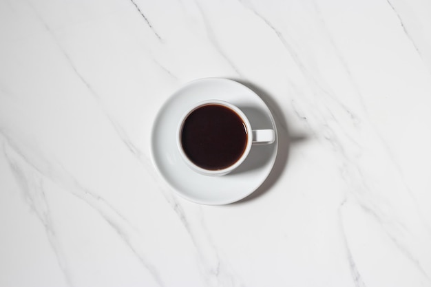 Chicchi di caffè sparsi e tazza di caffè espresso sullo sfondo di marmo