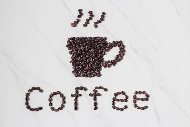 Scattered coffee beans and coffee espresso cup on marble backdrop