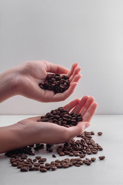 scattered coffee beans in female hands on a white background