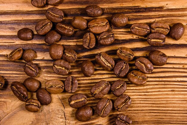 Scattered coffee beans on rustic wooden table Top view