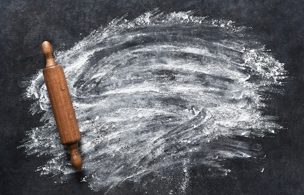 Photo scattered flour and rolling pin on the stone kitchen table. top view