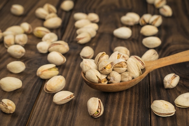 Scattered fried pistachios and a wooden spoon on the table.