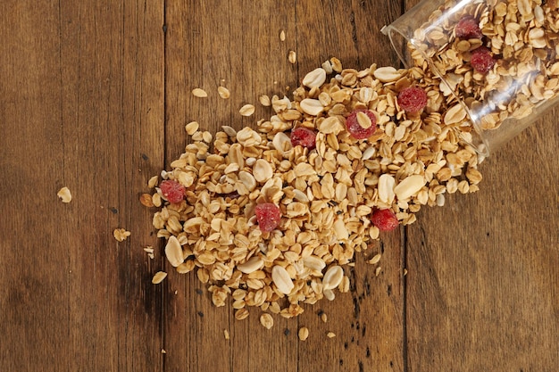 Scattered granola with dried fruits on a wooden table