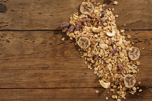 Scattered granola with dried fruits on a wooden table