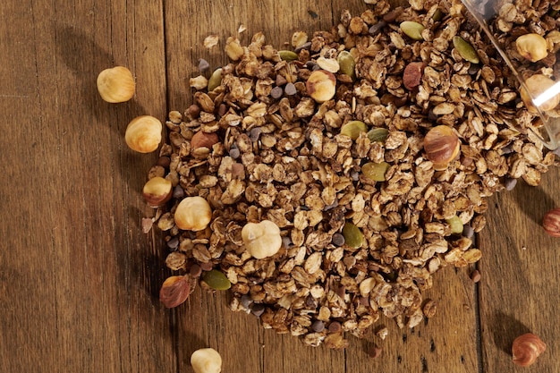 Scattered granola with dried fruits on a wooden table