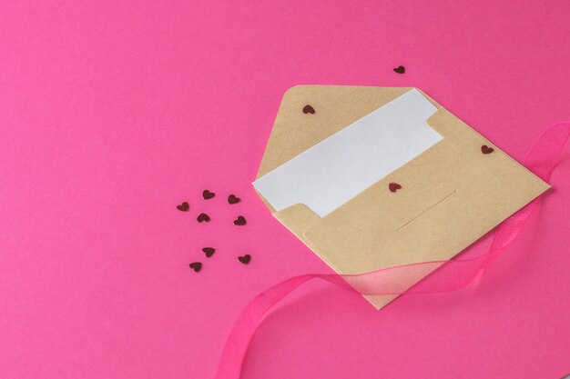 Photo scattered little hearts, an open postal envelope with a white sheet on a pink background.