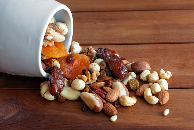 Scattered mixed nuts and dried fruit on dark wooden background. Healthy food and snack