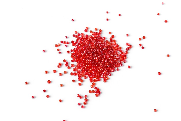 Scattered pile of red beads on a white background., top view.