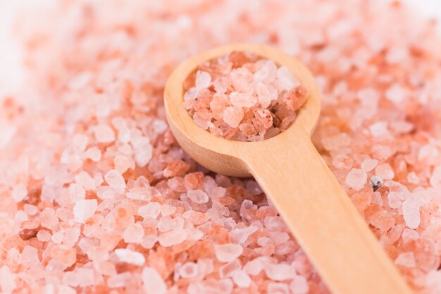 Photo scattered pink himalayan salt wooden spoon