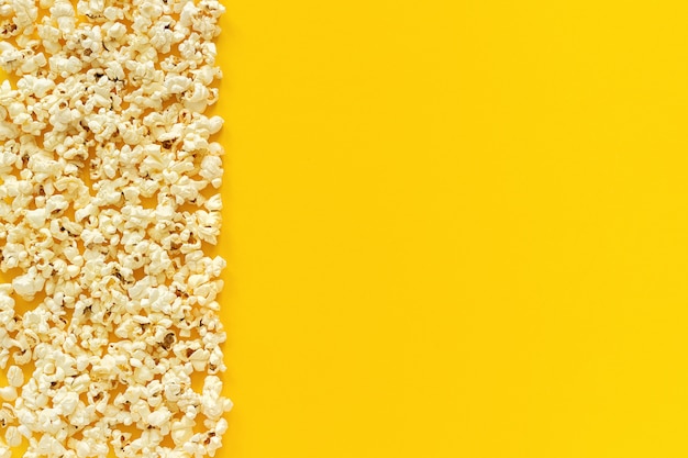 Scattered popcorn border left edge and empty space on yellow paper background. 