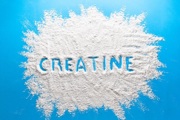 Scattered powder with the word creatine written on it on a blue background