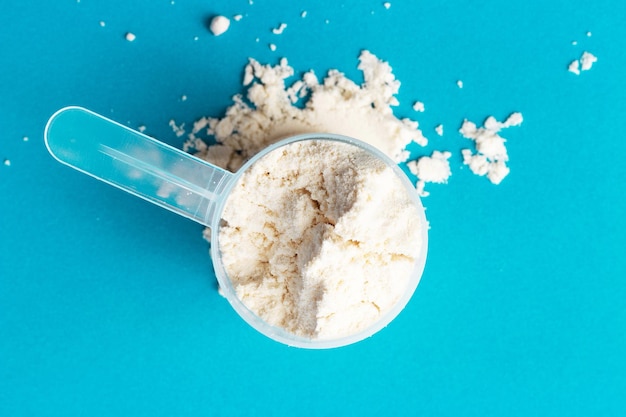 Photo scattered protein in scoop on a blue background close-up top view