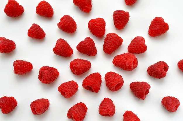 Scattered raspberries on a white background