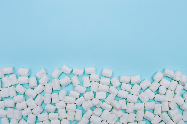 Scattered white marshmallows on blue paper