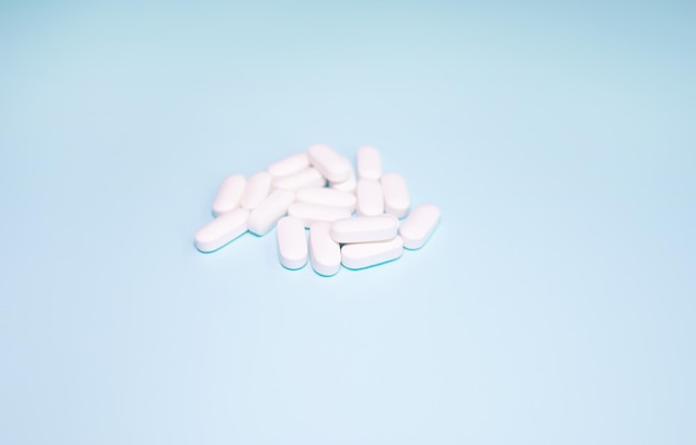 Разбросанные белые таблетки на синем фоне. Концепция медицины, фармации и здравоохранения.