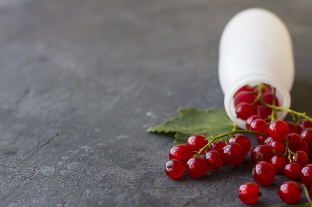 A scattering of red currants falling from a bottle