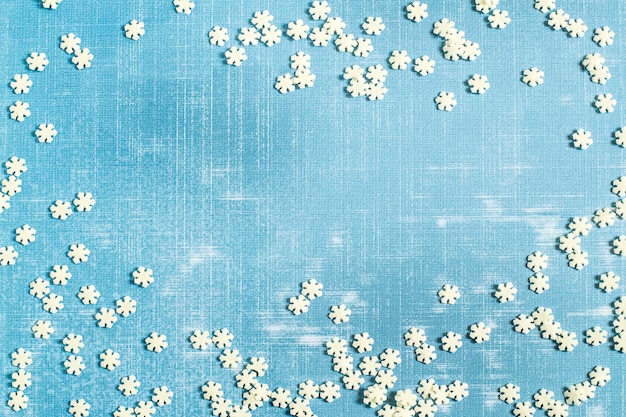 Scattering of sugar snowflakes on light blue textured shabby surface with space for text
