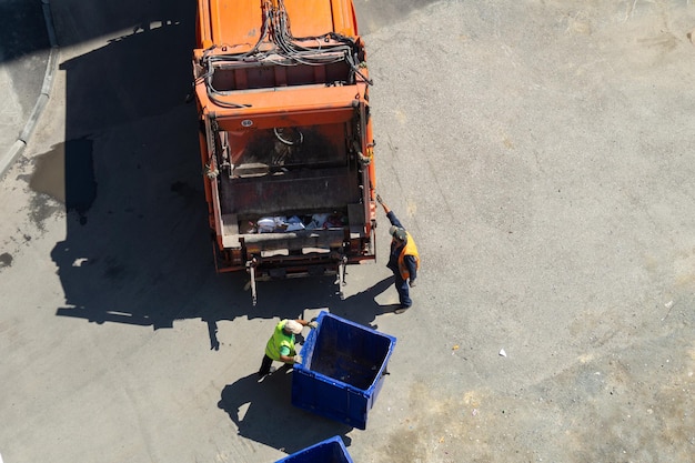 Scavengers roll an empty garbage can from a garbage truck Garbage removal top view