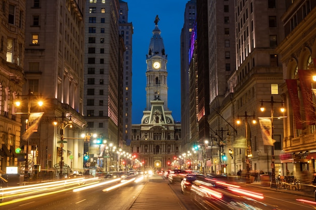 Scene of Philadelphia's landmark historic City Hall building at twilight time with car traffic light