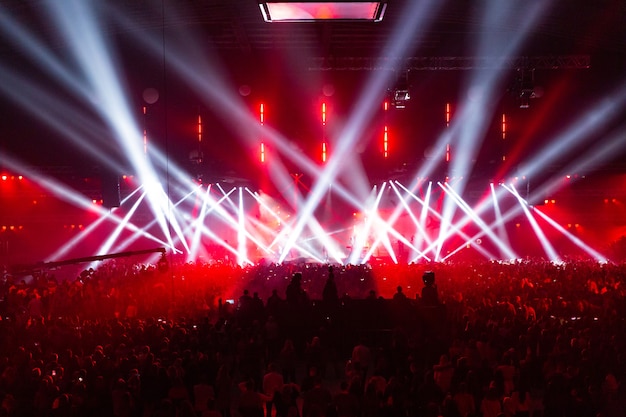 Scène verlicht door prachtige stralen van verlichtingsapparatuur. Het concertpubliek vermaakt zich in het midden van de grote zaal.