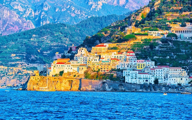 Scenery of Amalfi coast town at Tyrrhenian sea in autumn. Amalfitana coastline in Italy. Italian summer with beautiful blue water. Panoramic view. Holiday and vacation. Mediterranean landscape.