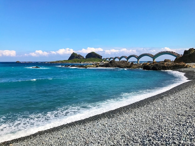Foto scenario della spiaggia di ghiaia, mare e ponte per l'isola di sanxiantai a taitung, taiwan.