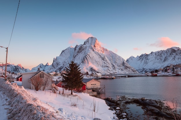 겨울에 Lofoten 섬의 풍경입니다. 스칸디나비아, 노르웨이의 해안선에 어촌 마을이있는 눈 덮인 산