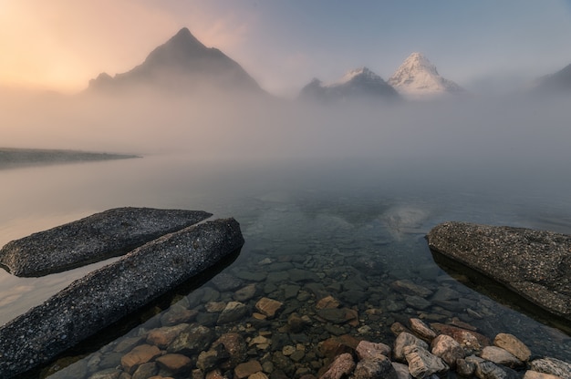 朝のマゴグ湖の霧の中でアッシニボイン山の風景