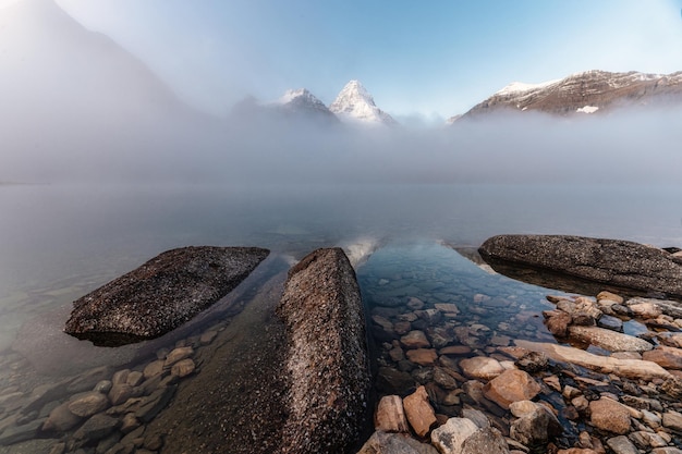 Scenery of mount Assiniboine with rocks in foggy on Magog lake at the morning Assiniboine provincial park Alberta Canada