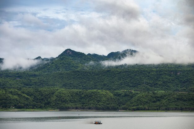 霧と雨季のダムでセーリングボートと山の風景