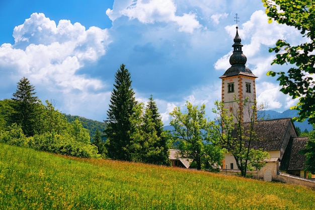 スロベニアのBohinj湖にある聖ヨハネバプテスト教会の近くの風景。スロベニアの自然。雲と青い空の眺め。夏の美しい風景。アルパイン旅行先。ジュリアンアルプス山脈