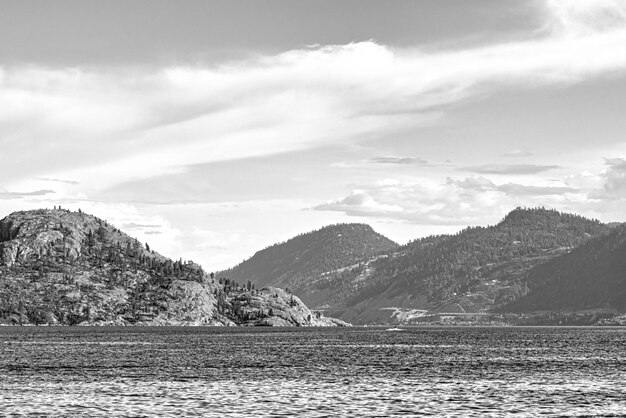 Photo scenery view of rocky slope over the lake in black and white