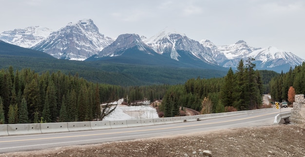 Paesaggio invernale vista della curva di nicholas morants sulla ferrovia del pacifico canadese e sul fiume bow con lo sfondo delle montagne rocciose delle tre sorelle
