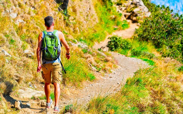 Scenery with man tourist on walk on Path of Gods in Italy at Naples. Amalfi coast and landscape with Tyrrhenian Sea at Italian Positano. Panorama of Amalfitana coastline in Europe. View in summer.