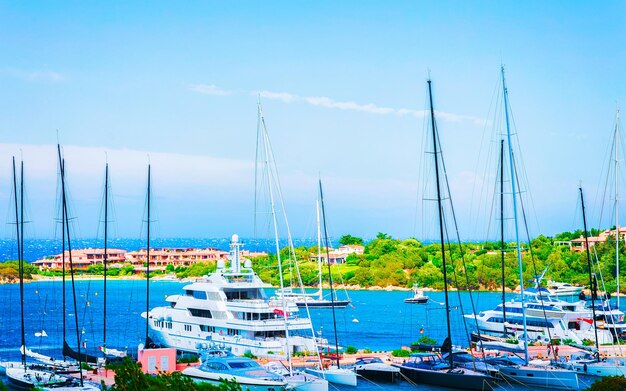 夏のイタリアのサルデーニャ島のポルトチェルボの地中海でのマリーナと豪華ヨットの風景。サルデーニャの船やボートでサルデーニャの町の港の風景を表示します。ミクストメディア。